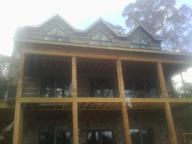 Dormers and porch framing on a large log home under construction — Roof Coating work by our crew in Carver