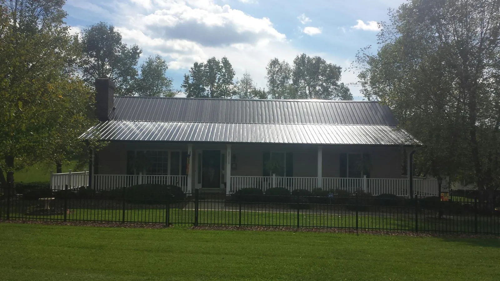 Gray metal roof on a brick ranch with a full width front porch — Gutter Guard Installation work by our crew in Carver